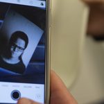 Student looks at phone's positive image of negative print.
