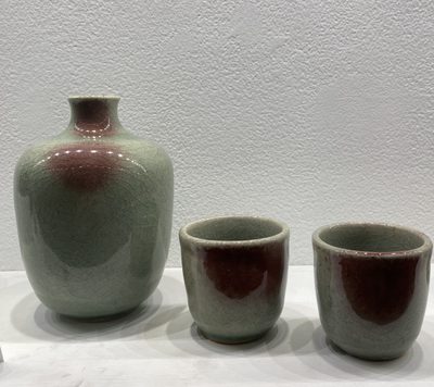 Ceramics from the Tea Dyad class -- A small green and brown vessel next to two small tea cups of the same color