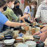 After each firing, students inspect every bowl (or mug) for defects, sand the bottoms, and pack them in crates.