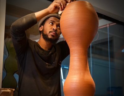 Artist Khalil Jannah sculpting a large vase of red clay