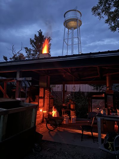 Nighttime photo of a glowing wood-fired kiln with the Carleton water tower in the background above