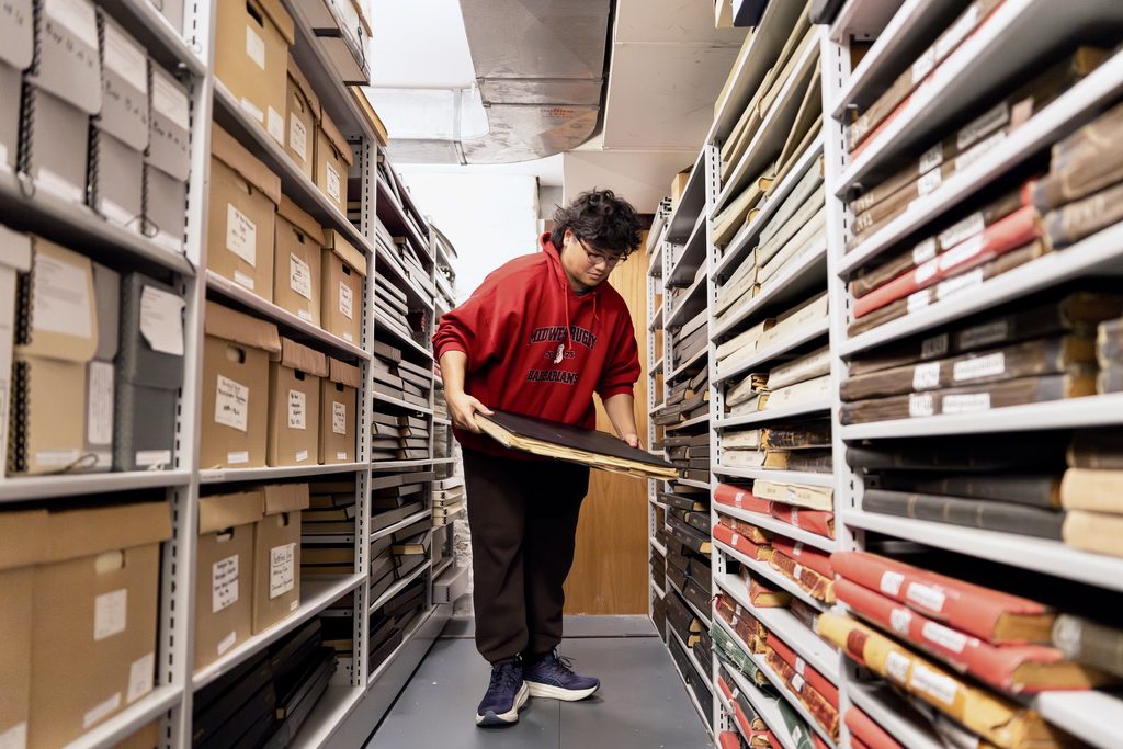 student admiring historical work in an aisle of boxes