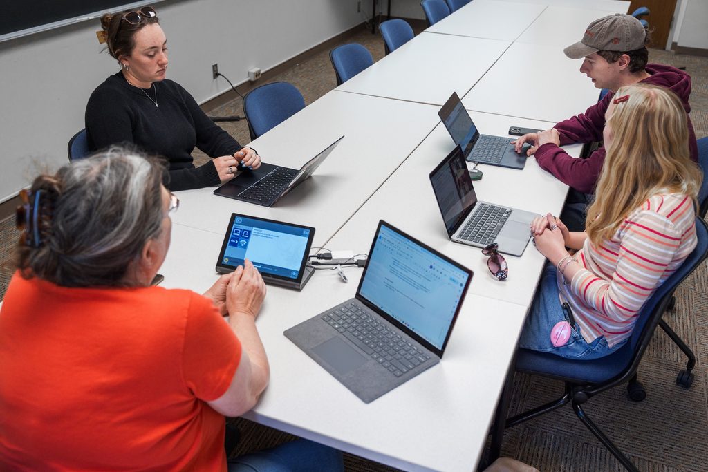 professor morse site with 3 students at a conference table