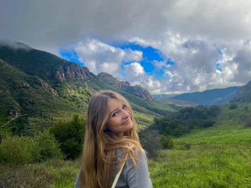 Image of young woman with long blonde hair looking backward over right shoulder