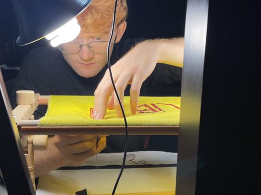 Student stitches a pattern into fabric