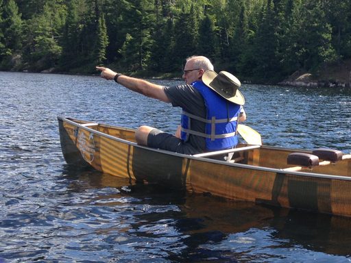 Randy Bass in sitting in canoe pointing in direction