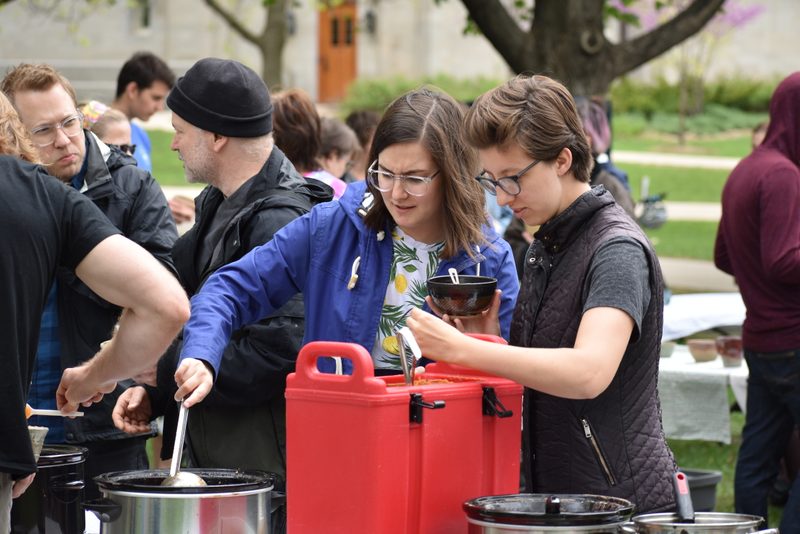 Students serve soup into bowls.