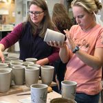 Two workshop participants inspect cups to be decorated.