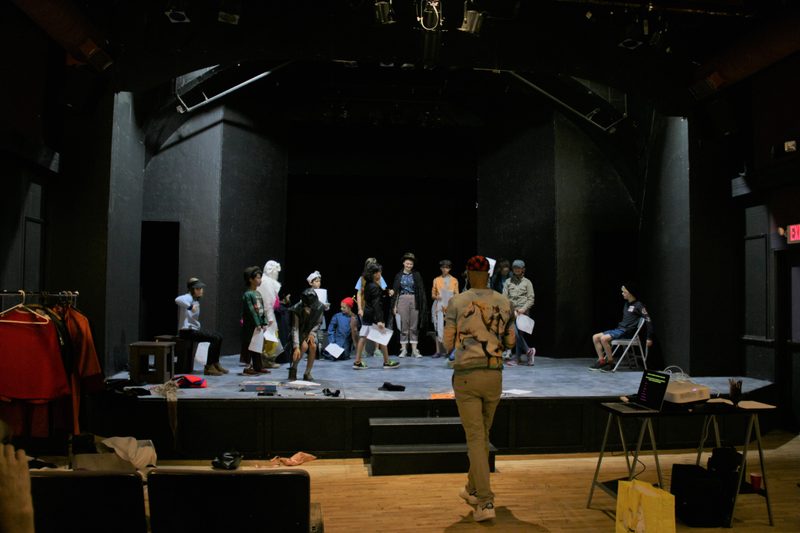 Participants prepare to share their characters. Approximately 15 participants gather on stage to share their characters. 2Fik stands in front of the stage.