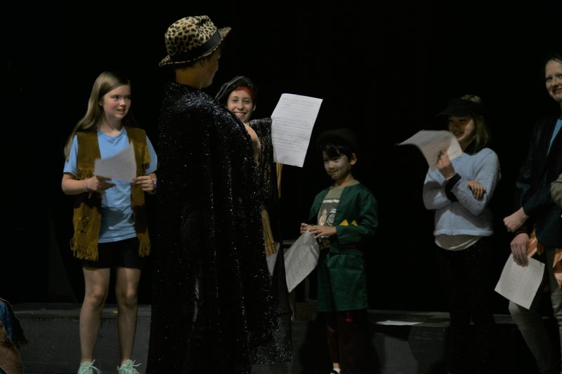 Workshop participants present their characters. Approximately six participants in the photo, some smiling and laughing.