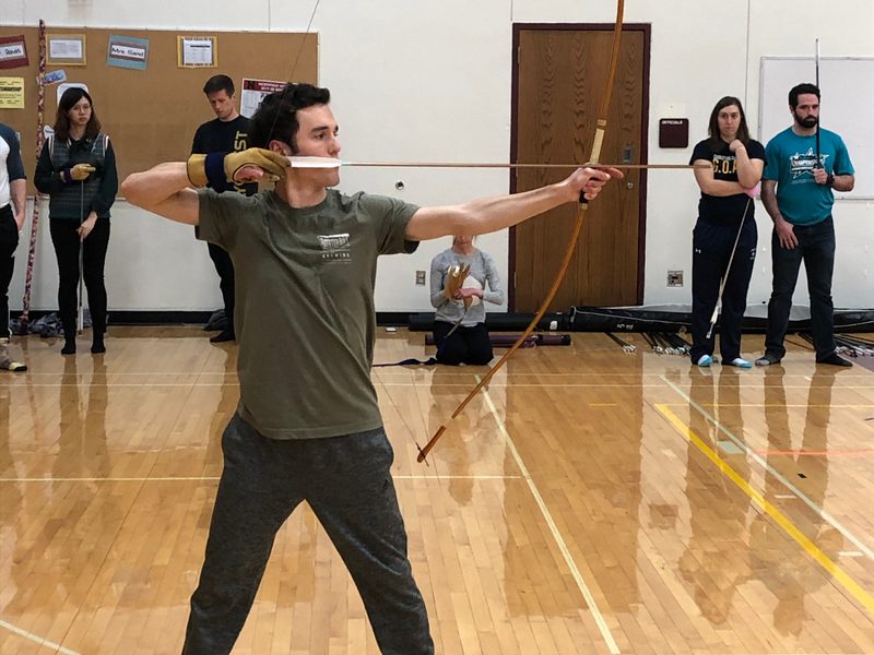 Kyudo Practice. A student draws an arrow as others look on.
