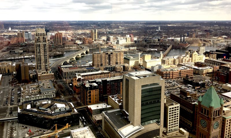 View from the Alumni Downtown Luncheon. View of downtown Minneapolis from a tall building in downtown. Foshay Tower, Mill City Museum, Mississippi River, and Stone Arch Bridge are visible.