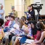 A group of seated audience members looks at a program