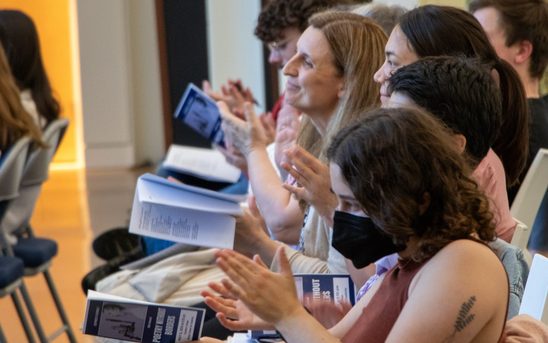 A group of audience members claps at the end of a performance