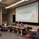 A photo of five students sitting in front of a 