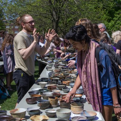 students examine pottery bowls on an outside table