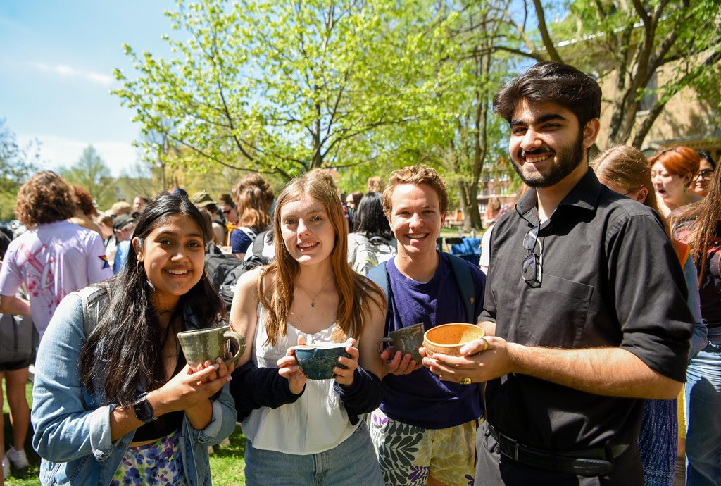 Students outdoors holding ceramic mugs and bowls