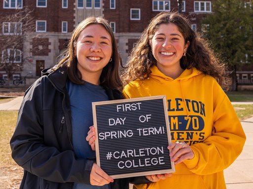 Two students smiling and holding a sign saying 