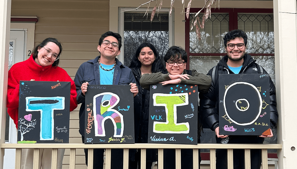 Students standing behind a sign that reads TRIO