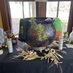 Black pot with moss growing around it, and other candles