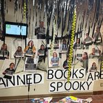 Wall full of photos who are noting spooky books. Streamers hanging down