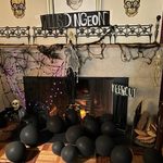 Fireplace covered with black balloons, a skeleton, and signs that say 