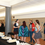 Students standing in the hall next to a table of food