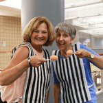 Two women each holding an egg on a spoon