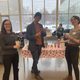 Three people standing around a table that has hearts on the tablecloth