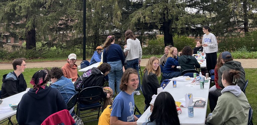 Students gathered around picnic tables on the lawn in front of Leighton Hall.