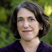 Headshot of Prof. Serena Zabin looking directly at the camera with a smile. She is wearing a dark purple top and is posed in front of greenery.