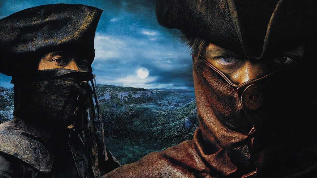 Promotional image from the movie Brotherhood of the Wolf. Two men close to the camera wearing tri-corn hats and leather coats with collars buttoned up to their eyes. The person on the right is looking directly at the camera and wearing a brown coat. The person on the left is oriented 3/4 to the camera and looking into the middle distance between the image viewer and the other man