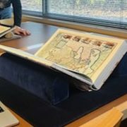 Map book sitting open propped on a book stand in the Gould Library Special Collections