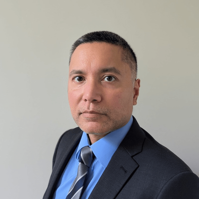 Shervon Cassim '00
Looking directly into camera, wearing a dark suit with bright blue collared shirt and coordinating striped tie