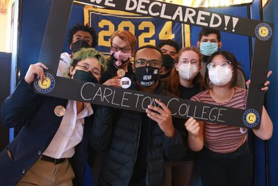 Eight people stand under a blue and yellow Class of 2024 banner, holding a sign to celebrate having declared their majors