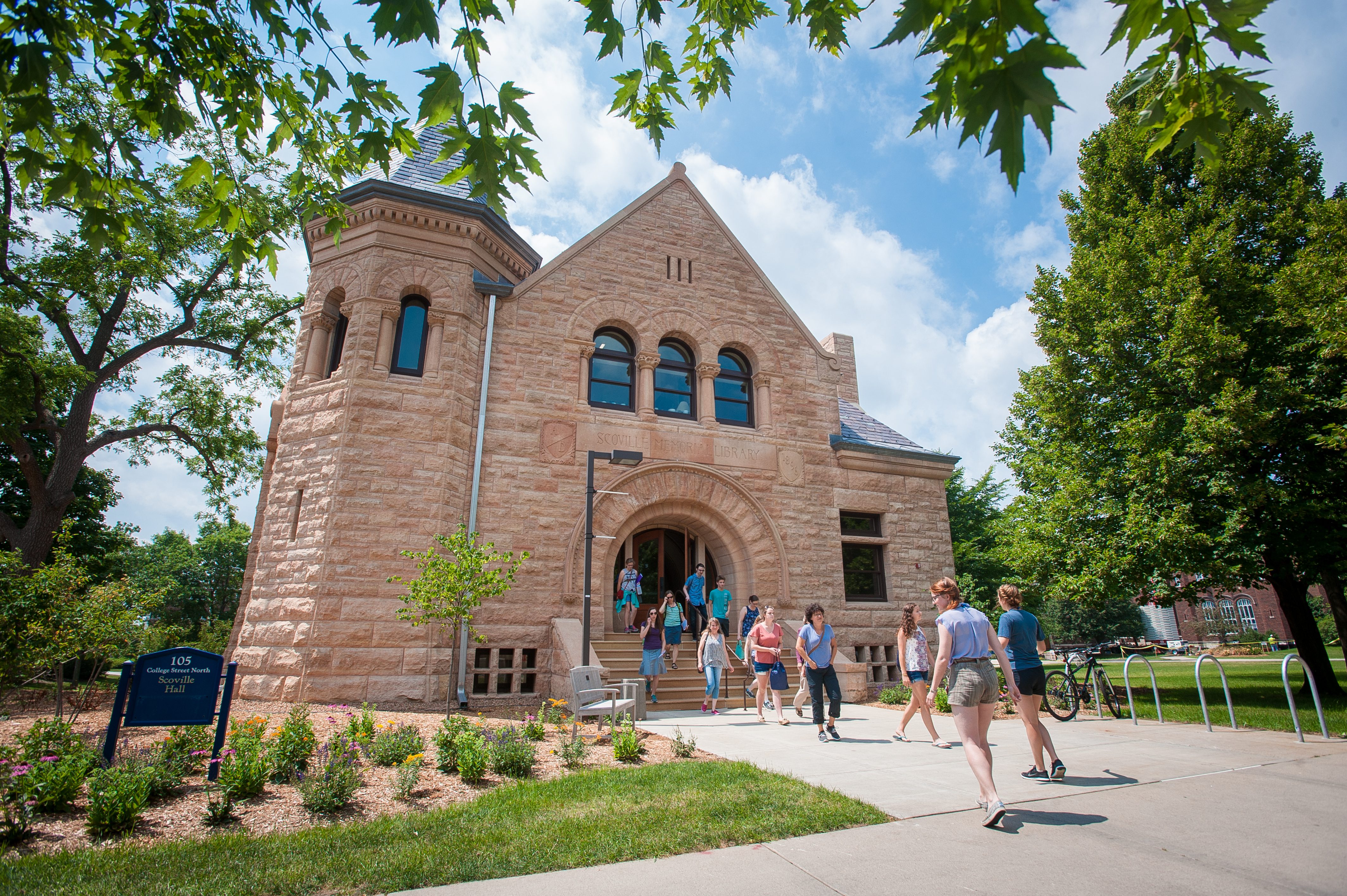 A campus tour group heading out of Scoville Hall on a sunny day