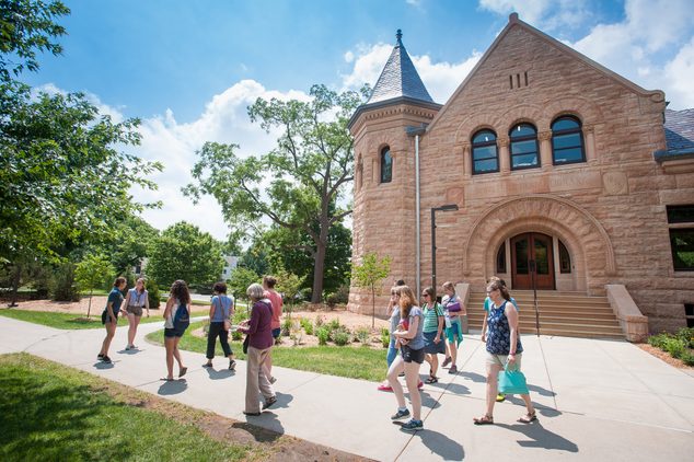 A student-led tour group leaves Admissions, most people in short sleeves