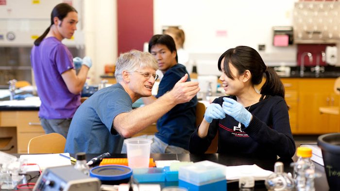 A professor helps a biology student with a lab procedure