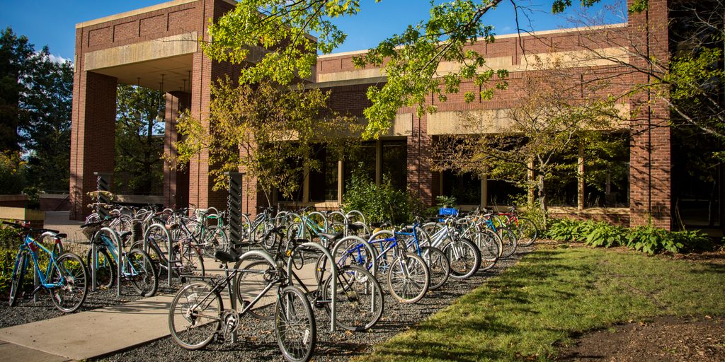 Many bikes line up at the bike racks by the main entrance to Gould Library