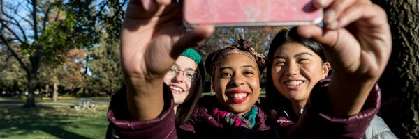 Three students smile as they take a selfie