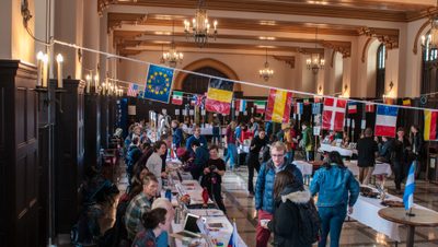 Students and professors at the World Studies Fair, with banners showing the flags of many nations