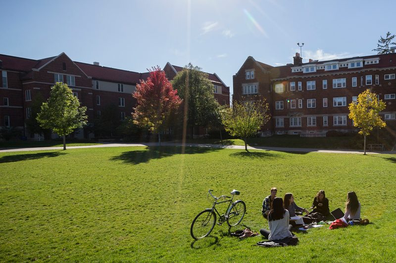 Students sit on the lawn of the Mini Bald Spot