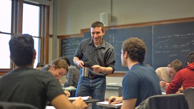 A professor stands in front of students during a class discussion