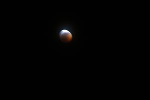 Close view of moon, red and white, blurred against a black sky