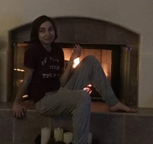 A girl lounges in front of a fire place