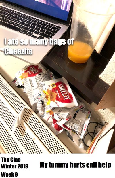 Picture of a computer on a desk with a glass of orange juice and many empty cheez it wrappers