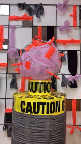 a sculpture with "caution" tape on it