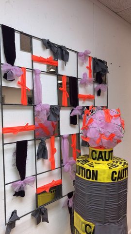a sculpture with "caution" tape and barbed wire on it