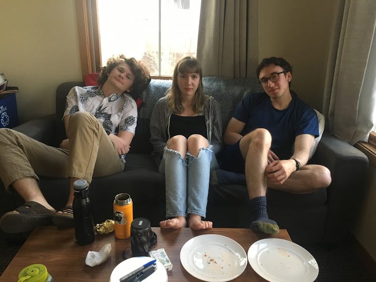 three students sitting together on a couch in townhouse living room 