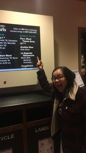An excited Asian American woman wearing glasses points to a screen with Rookies listed 